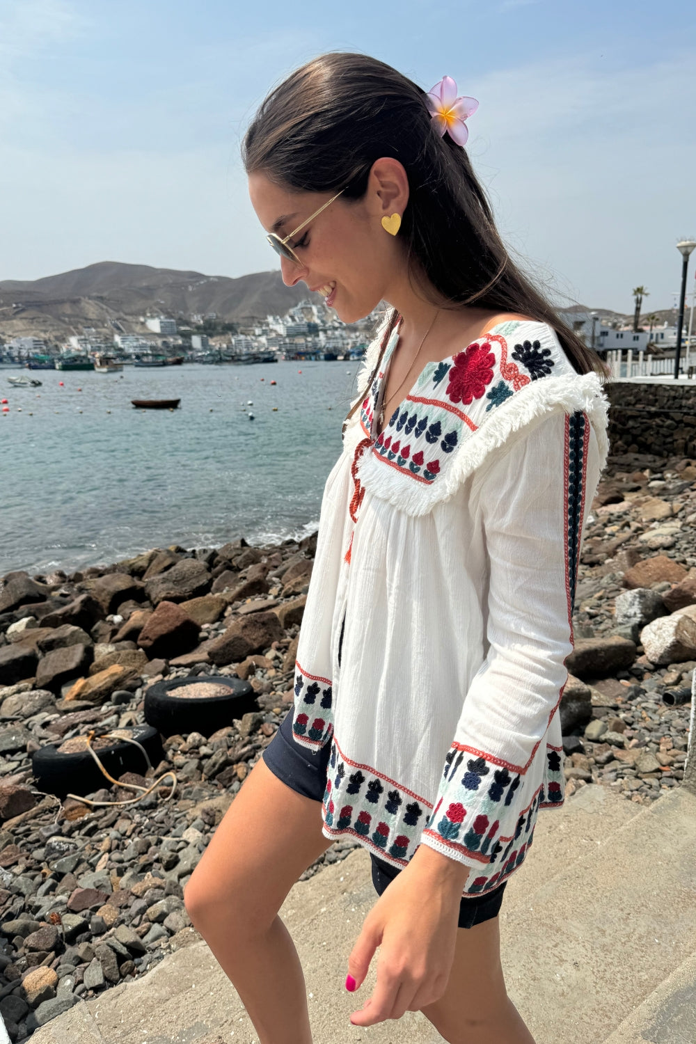 Blusa de manga larga con bordado de flores rojas, azules y celestes en el pecho, las mangas y la espalda. Un encantador pompón en el centro del pecho le da un toque especial y único.