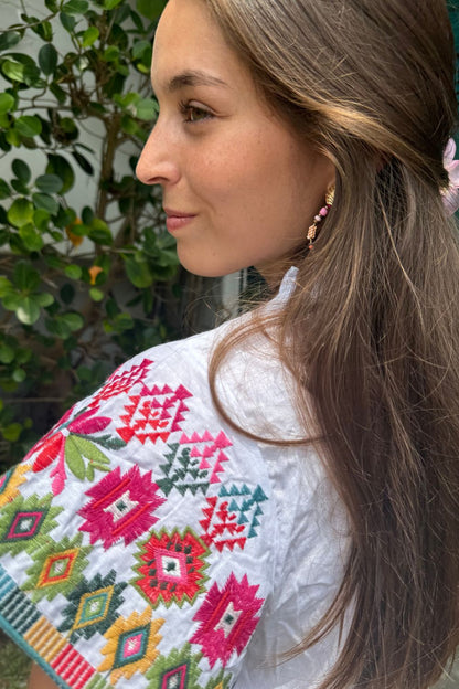 Blusa blanca con mangas completamente bordadas en una mezcla vibrante de colores.
Un diseño único y lleno de energía, perfecto para darle un toque colorido a tu look.