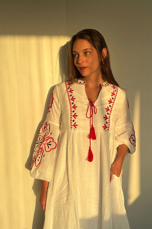Vestido blanco de manga larga con bordados rojos en las mangas y el pecho. Un elegante pompón rojo en el centro del pecho añade un toque único y vibrante.